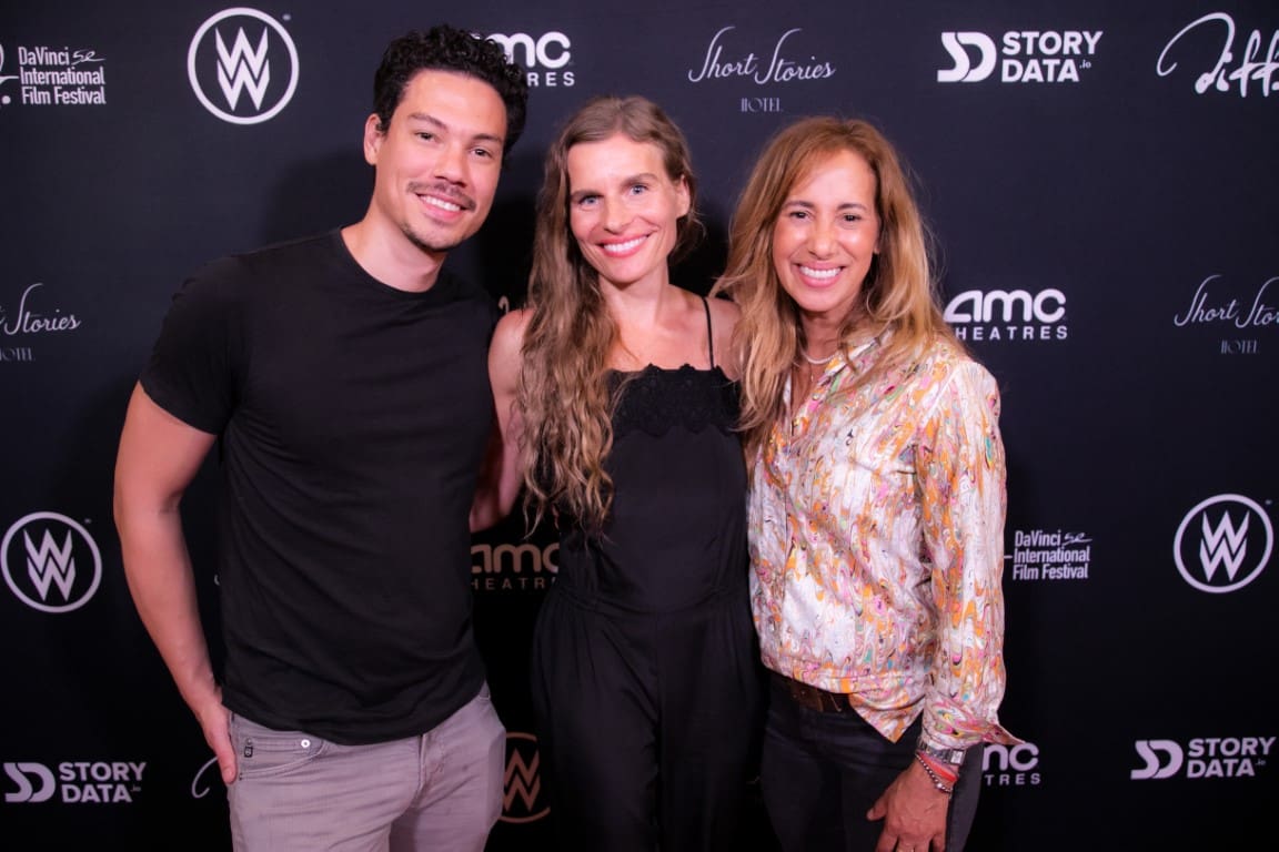A photo of individuals smiling on the red carpet.