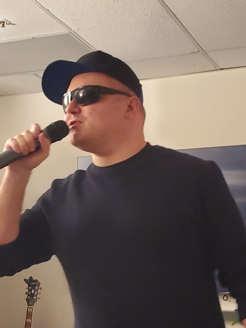 A photo of an individual singing into a microphone.